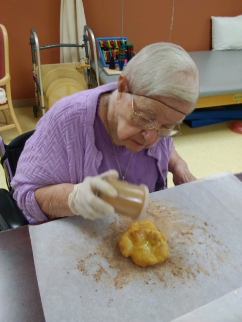 Older woman sprinkling cinnamon on elephant ear pastry