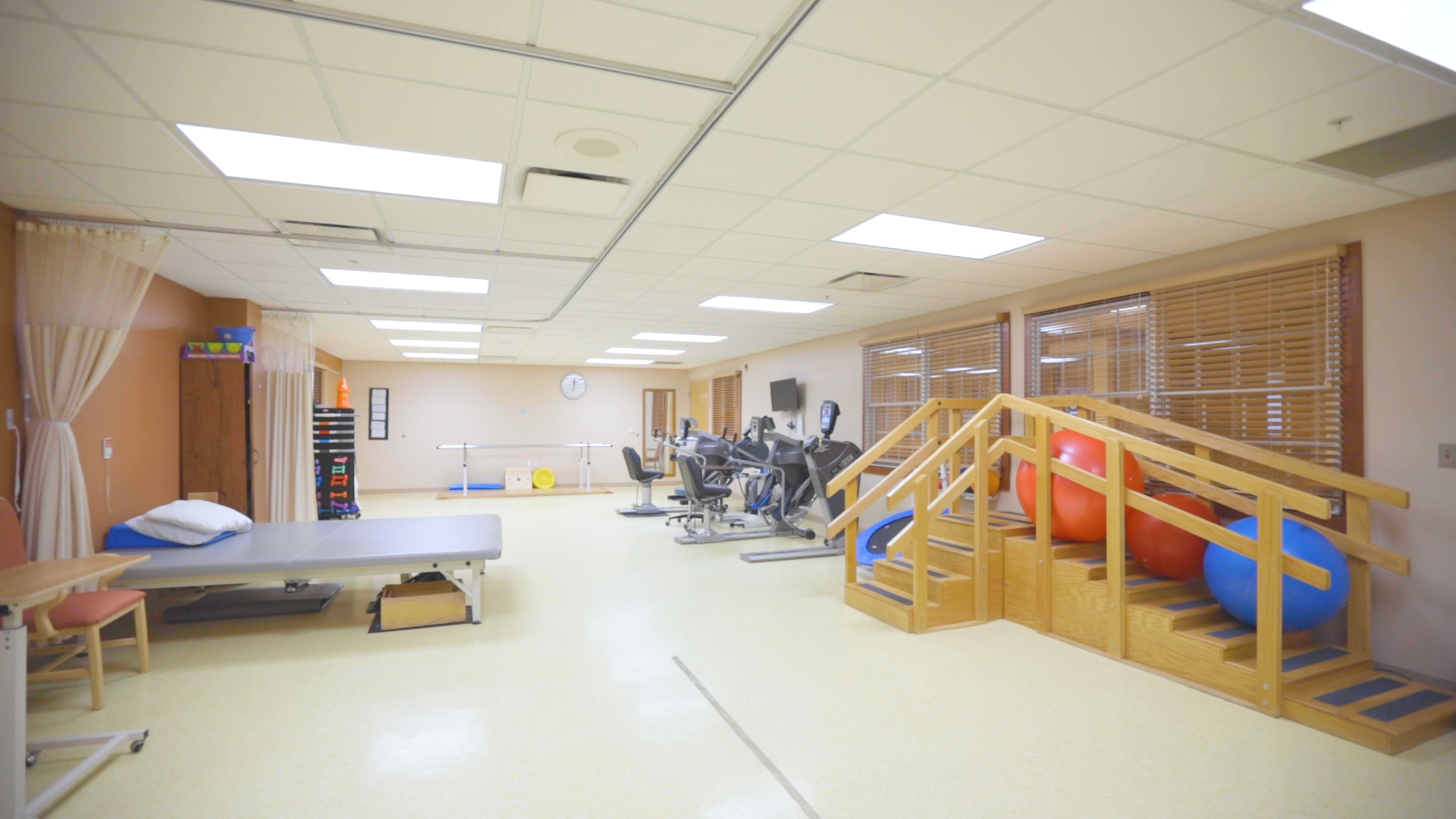 Treatment table, recumbent bike and wooden ladder in the gym.